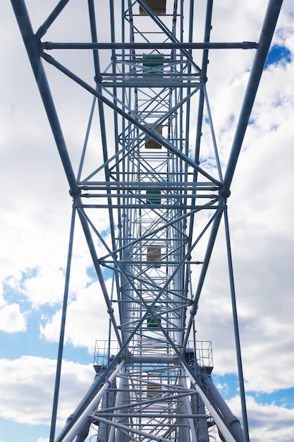 Parte da construção da roda gigante contra o céu azul com nuvens brancas, vista de dentro.