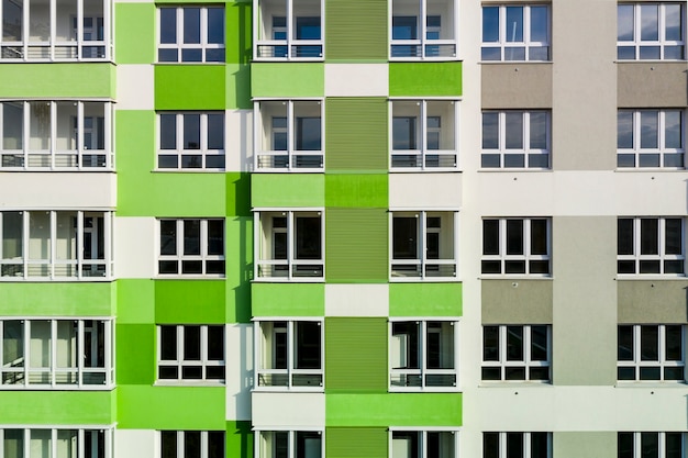 Parte da fachada com janelas de uma casa nova com paredes verdes acinzentadas