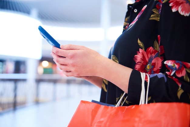 Parte da mulher usando o telefone celular durante as compras