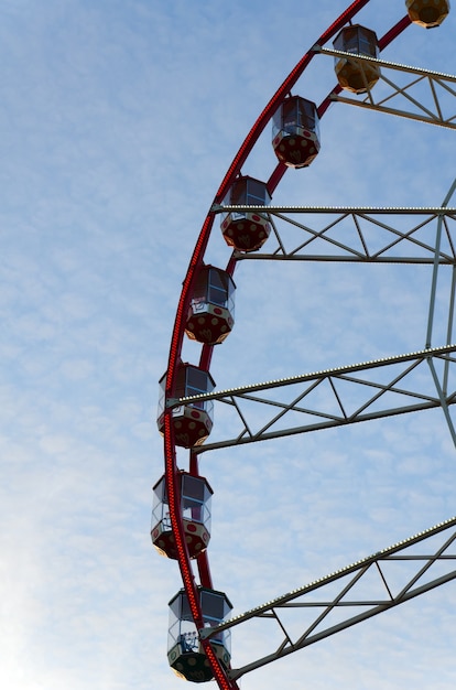 Parte da roda gigante com cabines no fundo de nuvens cirros e céu azul