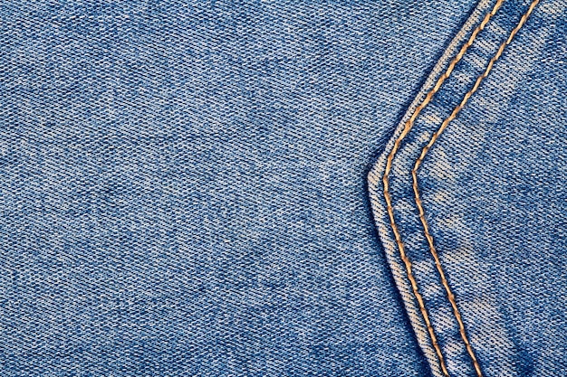 Parte de um bolso de fundo de jeans azul com costura e pontos de linha laranja