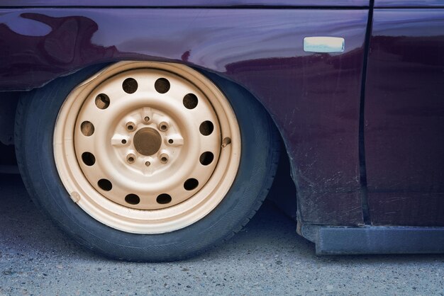 Foto parte de um carro roxo com suspensão pneumática na calçada fechamento da roda do carro