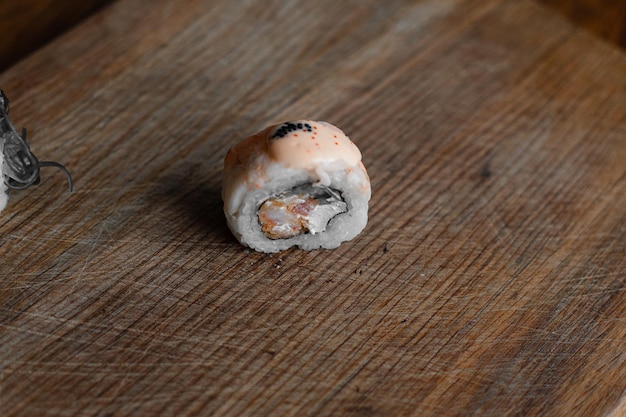 Parte de um rolo de sushi em um queijo Filadélfia de fundo de madeira