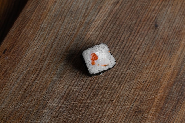 Parte de um rolo de sushi em um queijo Filadélfia de fundo de madeira