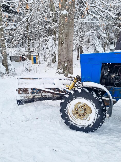 Parte de um trator azul com rodas grandes em uma floresta de neve