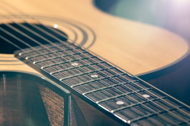 Parte de um violão, braço da guitarra com cordas em um fundo preto com destaques.