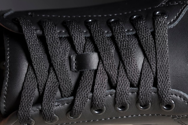 Parte de uma bota preta com cadarços um fragmento de sapatos escuros um pedaço de tênis
