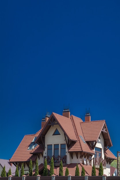 Parte de uma casa moderna de tijolos sob um telhado de azulejos em um céu. chalé com varanda. casa de madeira vivendo na natureza. acabamento em pedra natural