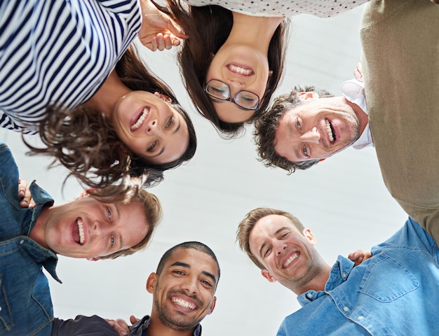Parte de uma equipe motivada foto de baixo ângulo de uma equipe de pessoas sorrindo positivamente para a câmera