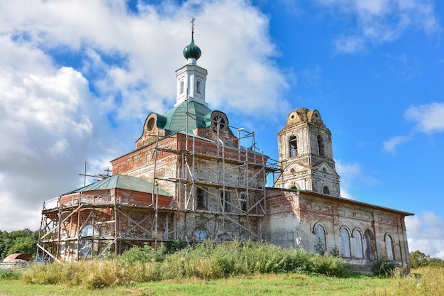 Parte de uma igreja restaurada com uma nova cúpula contra um céu nublado, cercada por vegetação, close-up