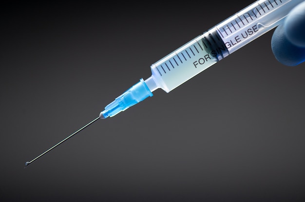 Parte de uma seringa médica com vacina de coronavírus e uma agulha close-up