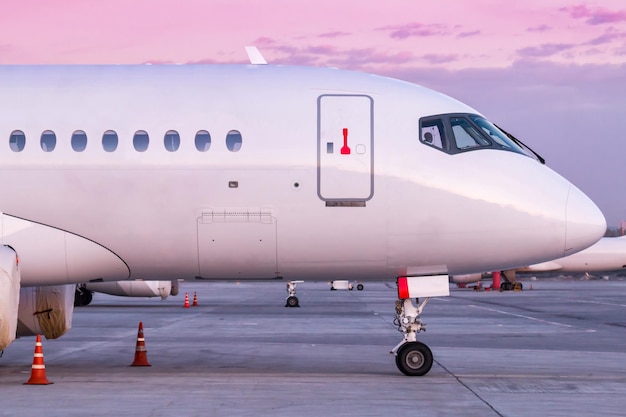 Parte delantera del avión de pasajeros moderno blanco en la plataforma del aeropuerto por la mañana