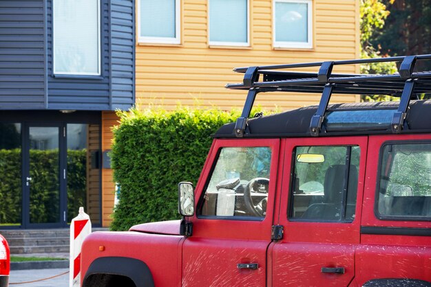 La parte delantera de un jeep rojo frente a una casa