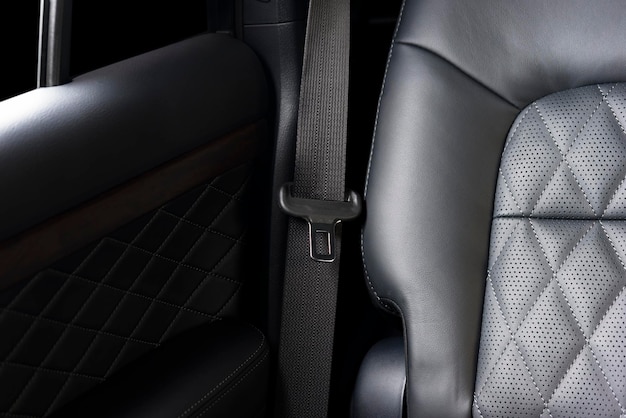 Parte del detalle del asiento de coche de cuero negro con enfoque en los bloqueos del cinturón de seguridad interior de automóvil de lujo moderno