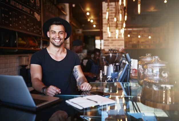 Parte de la diversión es crear nuevos menús Foto de un joven apuesto que trabaja detrás del mostrador de una cafetería