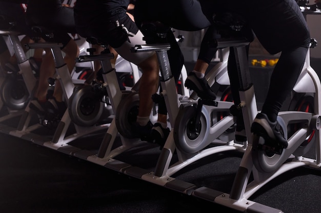 Foto parte inferior de bicicletas estáticas en un club deportivo de gimnasio, personas en bicicleta, hacer ejercicio, entrenamiento