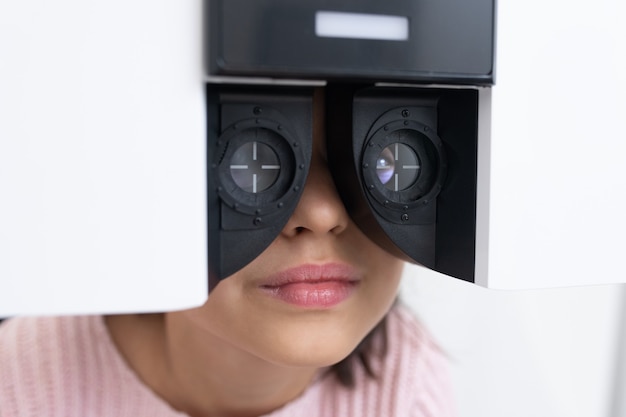 Foto parte inferior do rosto de uma adorável garotinha tendo sua visão verificada em frente a um novo equipamento oftalmológico em clínicas modernas