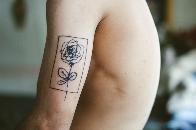 Parte intermediária de uma pessoa com tatuagem na mão