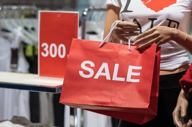 Foto parte del maniquí femenino vestido con ropa casual que sostiene la bolsa de compras de papel de ventas