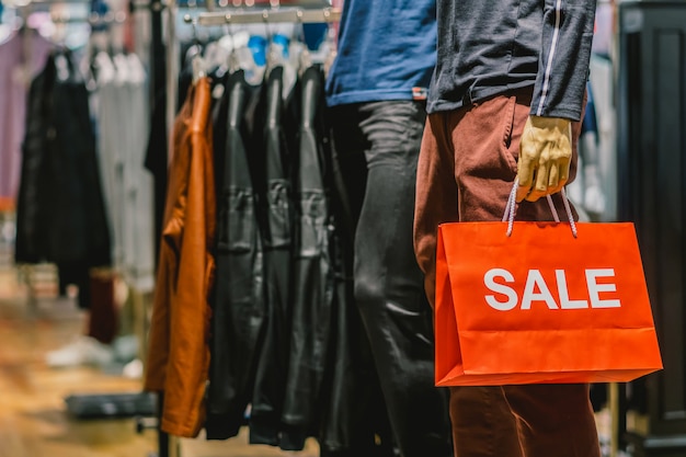 Parte del maniquí masculino vestido con ropa casual con el bolso de compras de papel Sales