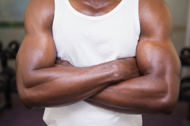 Parte média de um homem musculoso com os braços cruzados