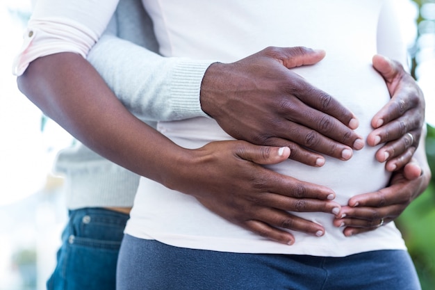 Parte média do homem junto com a barriga tocante da mulher