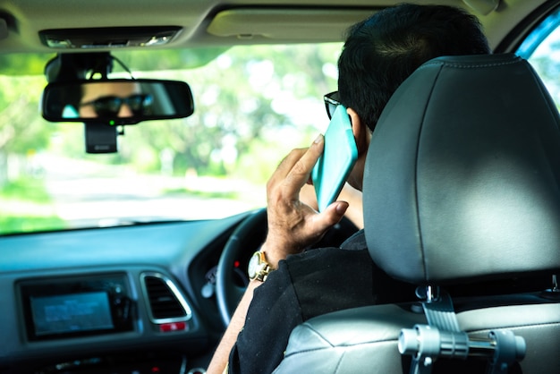 Parte posterior del hombre usa el teléfono móvil inteligente en el automóvil