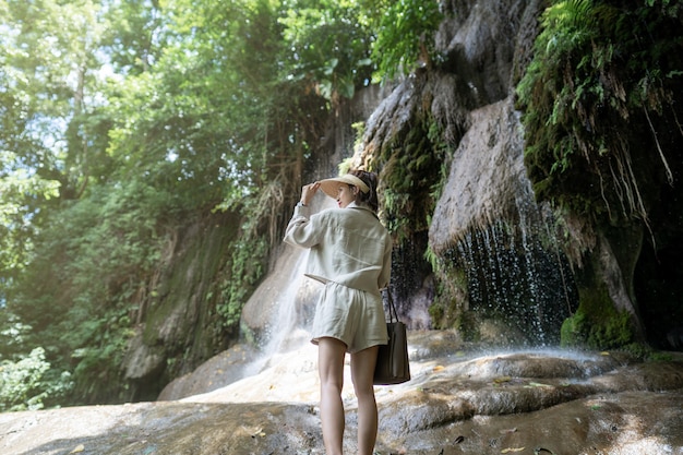 Parte posterior de la mujer con cascada en la selva tropical con roca cascada Saiyok noi