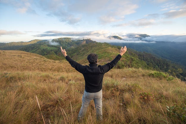 Parte posterior del soporte para hombre feliz en la cima de la montaña, mirando con niebla y nubes a Doi Langka Luang, provincia de Chiang Rai. enfoque suave.