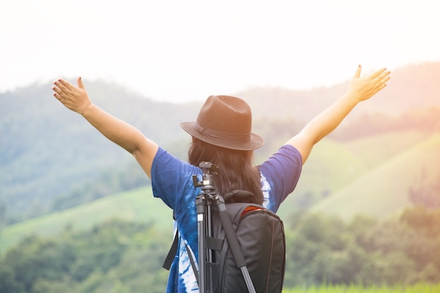 la parte posterior del soporte de la mujer feliz en la montaña del punto de vista con el fondo de la naturaleza.