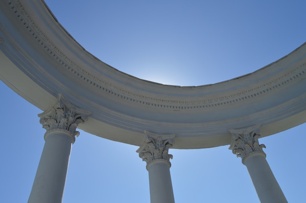 Parte de una rotonda blanca con columnas contra un cielo azul en un día soleado.