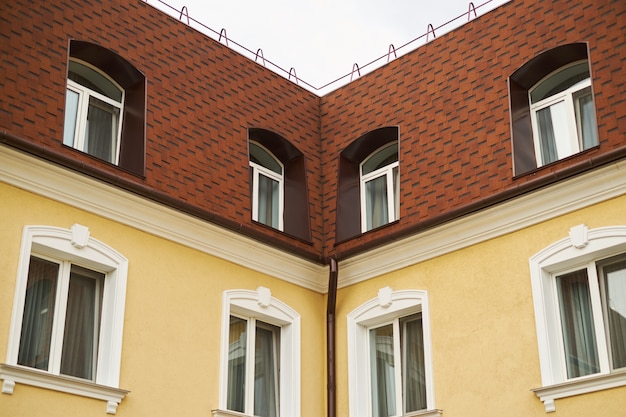 Parte superior de dos fachadas de casa un cielo blanco techo rojo