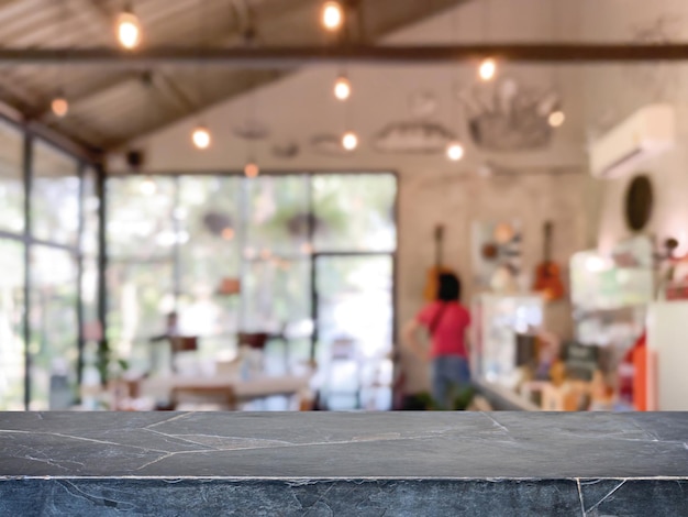 La parte superior de la mesa de piedra de mármol negro vacía y el fondo interior del restaurante y la cafetería de la cafetería borrosa se pueden usar para exhibir o montar sus productos