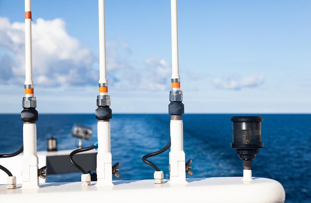 Parte superior del yate con luces de señal de antenas de navegación durante el día contra el fondo del mar y el cielo