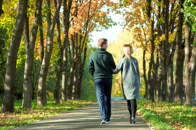 Parte traseira da garota e cara mão no amor. conceito de amor, relacionamento, família e pessoas - casal feliz andando no parque de verão