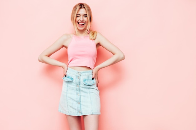 Parte traseira da jovem linda loira sorridente em roupas da moda de verão mulher despreocupada sexy posando perto da parede rosa no estúdio modelo positivo se divertindo dentro de casa alegre e feliz
