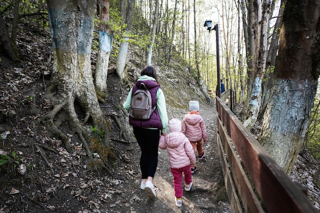 Parte traseira da mãe com crianças pequenas caminhando ao ar livre na natureza da primavera