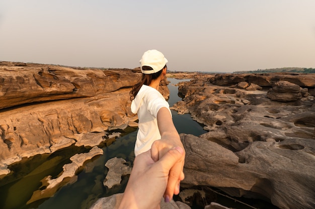 Parte traseira da mulher asiática de mãos dadas com o casal na falésia da rocha no grand canyon à noite. sam phan bok, ubon ratchathani