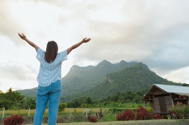 Parte traseira da mulher está desfrutando com a beleza natural da montanha e do céu enquanto ela viaja nas férias.