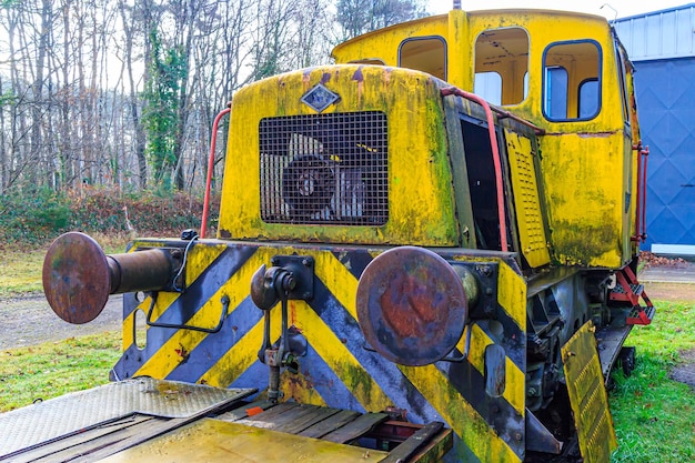 Parte traseira da velha cabine de controle de trem arruinada amarela em trilhos fora de uso em paradas de acoplamento de estação antiga e carregamento de plataforma plana enferrujada e corroída metal dia nublado de outono em Como Limburg Bélgica