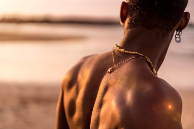 Parte traseira do homem étnico negro musculoso nas férias de verão à beira-mar, sentindo-se livre