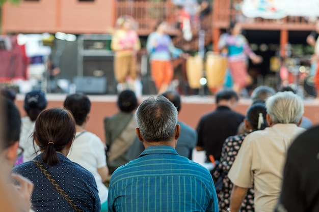 Foto parte traseira do público sentado e ouvindo os speackers no palco; conceito de evento e seminário