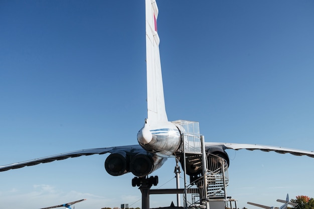 Foto parte trasera del avión raro con grandes turbinas y escalera a la entrada.