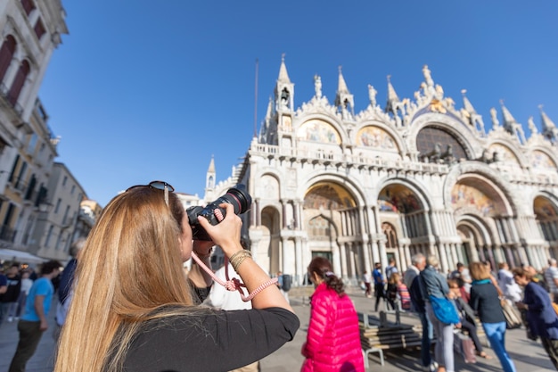 Parte trasera de una joven viajera que busca tomar fotos con una cámara digital de hermoso arte histórico