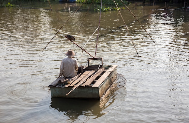 parte trasera del viejo pescador flotando en el río y la pesca