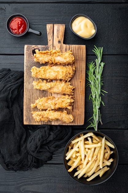 Partes de rayas de pollo crujiente frito sobre mesa de madera negra