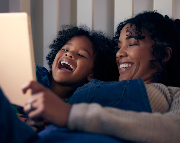 Participar en algo de diversión virtual antes de acostarse Fotografía de una mujer y su hijo mirando algo en una tableta digital antes de acostarse