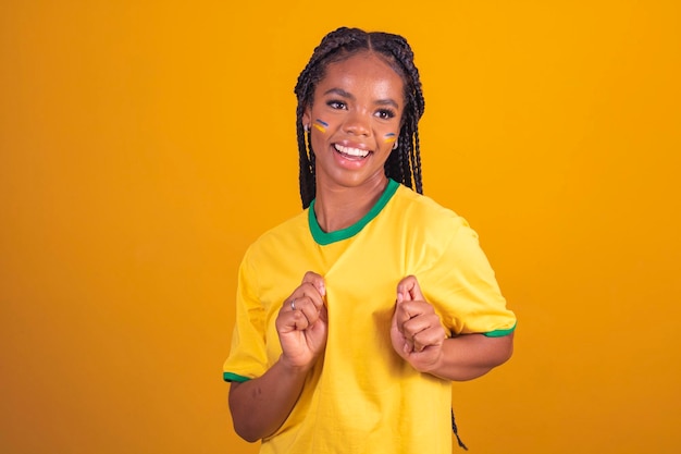 Partidario brasileño Fanático de la mujer brasileña celebrando el fútbol o el partido de fútbol con fondo amarillo Colores de Brasil