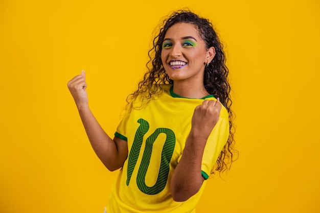 Partidario brasileño Fanático de la mujer brasileña celebrando el fútbol o el partido de fútbol con fondo amarillo Colores de Brasil