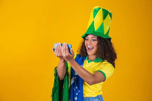 Partidario de la selección brasileña de fútbol celebrando un gol mirando el teléfono inteligente